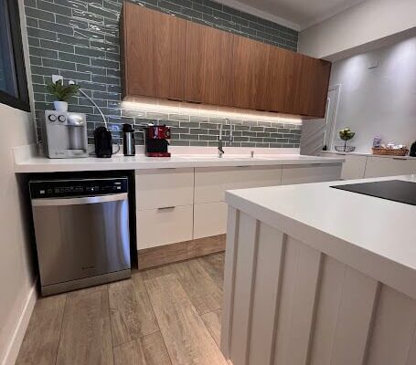 Cozinha Planejada com Ilha no MDF Branco Diamante fosco com ripado, balcões inferiores no branco e armários superior no MDF amadeirado Jatobá Brasileiro. Instalado pela DECORATA em apartamento no Canto do Forte