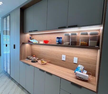 Cozinha Planejada no MDF Beige com nicho no amadeirado Itapuã e iluminação em LED. Cristaleira com portas de vidro incolor e perfil Bronze, instalada pela DECORATA em Santos No Canal 3