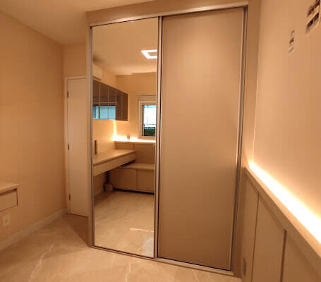 quarto planejado com portas de correr com amortecimento suave, portas de espelho e de MDF com iluminação no painel