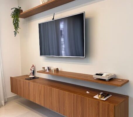 Painel de TV com rack suspenso e prateleiras flutuantes no amadeirado instalado pela DECORATA em Santos