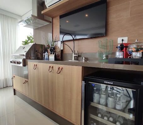 Varanda Gourmet amaderiada com puxadores em couro da ZEN e painel de TV amadeirado instalado no canto do forte pela DECORATA